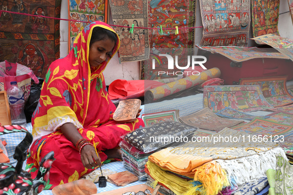 A woman paints a traditional and mythological painting for sale at a roadside during the Durga Puja festival in Kolkata, India, on October 1...