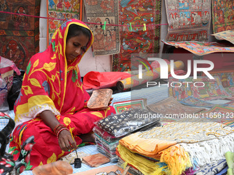 A woman paints a traditional and mythological painting for sale at a roadside during the Durga Puja festival in Kolkata, India, on October 1...