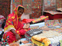 A woman paints a traditional and mythological painting for sale at a roadside during the Durga Puja festival in Kolkata, India, on October 1...