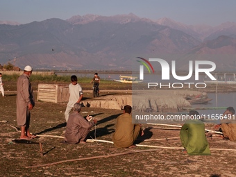 Kashmiri fishermen repair their boats during sunset at Wular Lake in Sopore, Jammu and Kashmir, India, on October 11, 2024. (