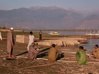 Kashmiri fishermen repair their boats during sunset at Wular Lake in Sopore, Jammu and Kashmir, India, on October 11, 2024. (