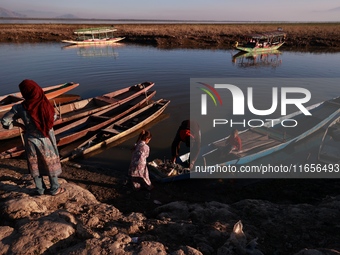 Kashmiri fishermen repair their boats during sunset at Wular Lake in Sopore, Jammu and Kashmir, India, on October 11, 2024. (