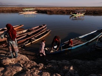 Kashmiri fishermen repair their boats during sunset at Wular Lake in Sopore, Jammu and Kashmir, India, on October 11, 2024. (