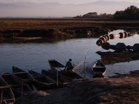 A boy from a fishing community removes water from a boat at Wular Lake in Sopore, Jammu and Kashmir, India, on October 11, 2024. (