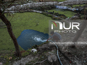 A boy drinks water from a pipe near a pond on the banks of Wular Lake in Sopore, Jammu and Kashmir, India, on October 11, 2024. (