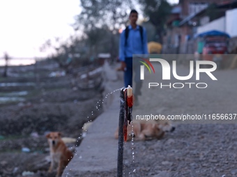 Water falls from a faulty tap as a boy walks on a road near Wular Lake in Sopore, Jammu and Kashmir, India, on October 11, 2024. (