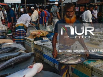 People gather at a wholesale fish market early in the morning near the Padma River in Mawa, Munshiganj, Bangladesh, on October 11, 2024. The...