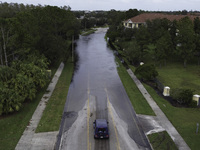 The street floods during Hurricane Milton in the Hunters Creek region, Florida, with water trapped between residents' homes and the lake, on...