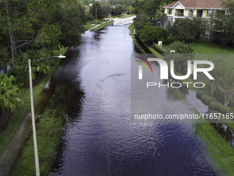 The street floods during Hurricane Milton in the Hunters Creek region, Florida, with water trapped between residents' homes and the lake, on...