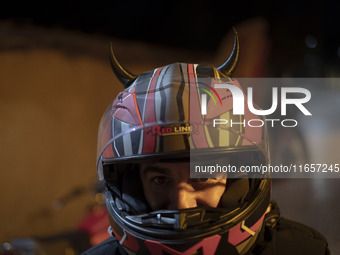 An Iranian motorcyclist poses for a photograph while standing on a path out of a garden in Shiraz, Iran, on October 8, 2024, at night.  (