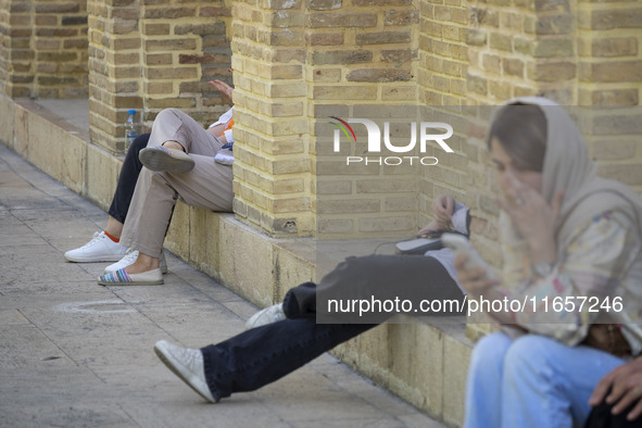 Young Iranian women sit near the tomb of the 14th-century Iranian poet, Hafez, in Shiraz, Iran, on October 8, 2024.  