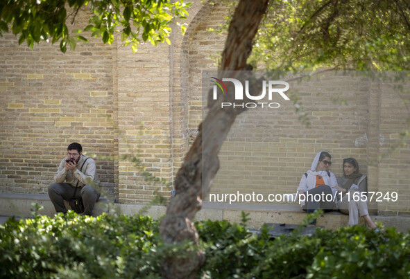 Two young Iranian women and a man sit near the tomb of the 14th-century Iranian poet, Hafez, in Shiraz, Iran, on October 8, 2024.  