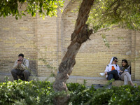 Two young Iranian women and a man sit near the tomb of the 14th-century Iranian poet, Hafez, in Shiraz, Iran, on October 8, 2024.  (