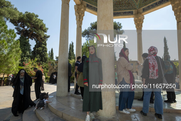 Young Iranian women stand next to the tomb of the 14th-century Iranian poet, Hafez, in Shiraz, Iran, on October 8, 2024.  