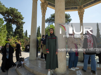 Young Iranian women stand next to the tomb of the 14th-century Iranian poet, Hafez, in Shiraz, Iran, on October 8, 2024.  (