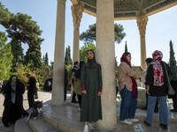 Young Iranian women stand next to the tomb of the 14th-century Iranian poet, Hafez, in Shiraz, Iran, on October 8, 2024.  (