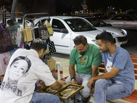 Young Iranian men play backgammon while sitting on a sidewalk outside a shopping center in Shiraz, Iran, on October 8, 2024, at night.  (