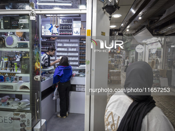 A young Iranian woman who is not wearing a mandatory headscarf shops at a cosmetic shop at a shopping center in Shiraz, Iran, on October 8,...