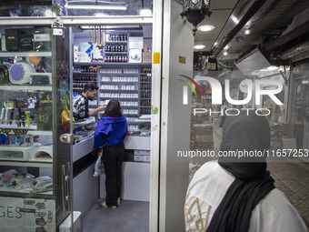 A young Iranian woman who is not wearing a mandatory headscarf shops at a cosmetic shop at a shopping center in Shiraz, Iran, on October 8,...