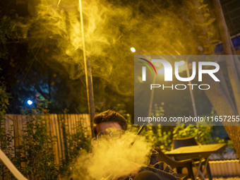 A young Iranian man puffs on a hookah while sitting at a garden-cafe in Shiraz, Iran, on October 7, 2024.  (