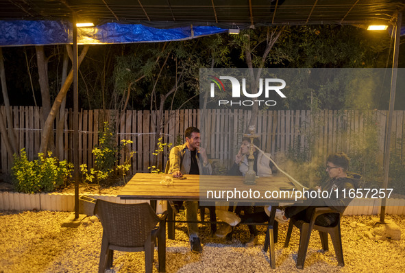 Young Iranian men sit together at a garden-cafe in Shiraz, Iran, on October 7, 2024, while Western countries express concern about a potenti...