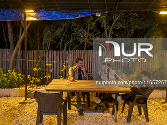 Young Iranian men sit together at a garden-cafe in Shiraz, Iran, on October 7, 2024, while Western countries express concern about a potenti...