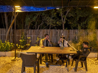 Young Iranian men sit together at a garden-cafe in Shiraz, Iran, on October 7, 2024, while Western countries express concern about a potenti...