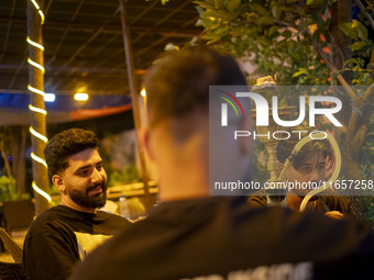 Young Iranian men sit together at a garden-cafe in Shiraz, Iran, on October 7, 2024, while Western countries express concern about a potenti...