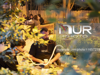 An Iranian man puffs on a hookah while sitting at a garden-cafe in Shiraz, Iran, on October 7, 2024. Western countries express concern about...