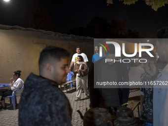 Iranian youths are outside an outdoor cafe in a garden in the city of Shiraz, Iran, on October 7, 2024.  (