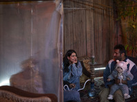 A young woman and a man carrying his child sit at a garden cafe in Shiraz, Iran, on October 7, 2024.  (