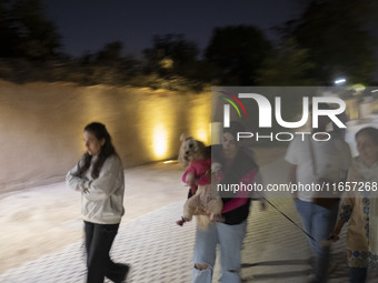 Iranian youths walk along a path while one of them carries her pet in Shiraz, Iran, on October 7, 2024. Western countries express concern ab...