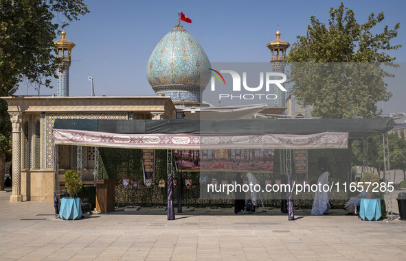 Two veiled Iranian women stand next to a portrait of the late leader of Lebanon's Hezbollah, Hassan Nasrallah, in a holy shrine in Shiraz, I...