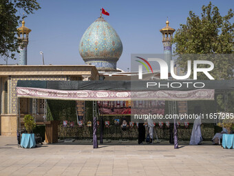 Two veiled Iranian women stand next to a portrait of the late leader of Lebanon's Hezbollah, Hassan Nasrallah, in a holy shrine in Shiraz, I...