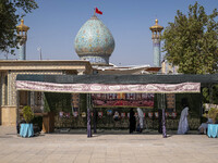 Two veiled Iranian women stand next to a portrait of the late leader of Lebanon's Hezbollah, Hassan Nasrallah, in a holy shrine in Shiraz, I...