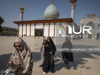 Veiled Iranian women walk along an area in a holy shrine in Shiraz, Iran, on October 8, 2024. Western countries express concern about a pote...