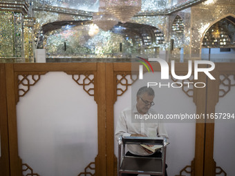 An Iranian man reads a copy of the Muslim holy book, the Koran, while sitting next to a tomb in a holy shrine in Shiraz, Iran, on October 8,...