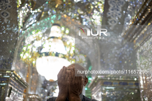 An Iranian man prays next to a tomb in a holy shrine in Shiraz, Iran, on October 8, 2024. While Western countries express concern about a po...