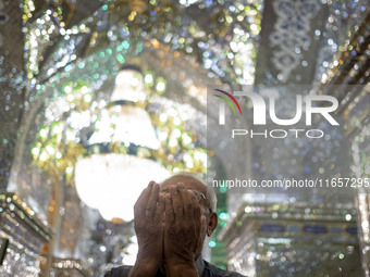 An Iranian man prays next to a tomb in a holy shrine in Shiraz, Iran, on October 8, 2024. While Western countries express concern about a po...