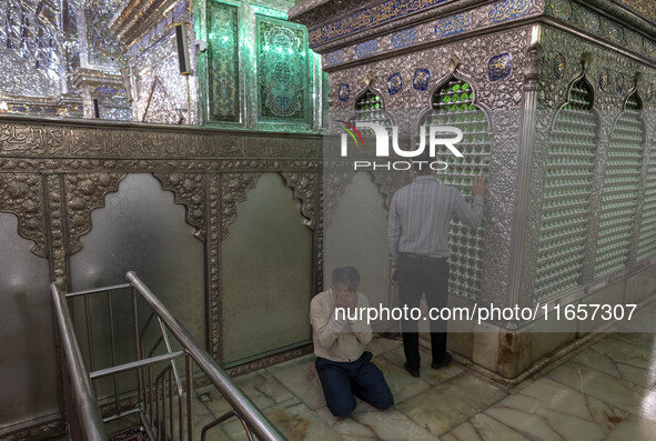 Two Iranian men pray next to a tomb in a holy shrine in Shiraz, Iran, on October 8, 2024. Western countries express concern about a potentia...