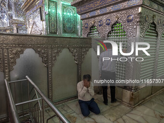 Two Iranian men pray next to a tomb in a holy shrine in Shiraz, Iran, on October 8, 2024. Western countries express concern about a potentia...