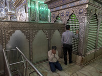 Two Iranian men pray next to a tomb in a holy shrine in Shiraz, Iran, on October 8, 2024. Western countries express concern about a potentia...