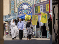 Two veiled Iranian women and a man walk past Lebanon's Hezbollah flags in a holy shrine in Shiraz, Iran, on October 8, 2024. While Western c...