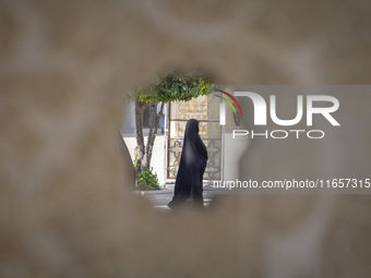 A veiled Iranian woman walks in a holy shrine in Shiraz, Iran, on October 8, 2024. While Western countries express concern about a potential...