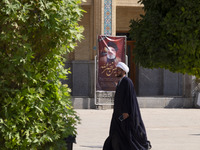 An Iranian cleric walks past a banner featuring a portrait of Lebanon's Hezbollah late leader, Hassan Nasrallah, in a holy shrine in Shiraz,...