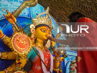 A woman offers sweets to an idol of the Hindu goddess Durga while offering prayers on the last day of the Durga Puja festival in Kolkata, In...