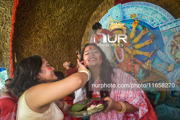 Hindu women apply ''sindhur,'' or vermillion powder, on each other's faces after worshipping the idol of the Hindu goddess Durga on the last...