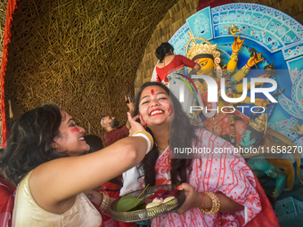 Hindu women apply ''sindhur,'' or vermillion powder, on each other's faces after worshipping the idol of the Hindu goddess Durga on the last...