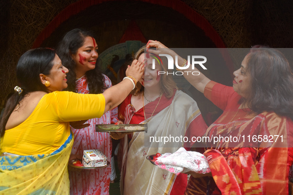 Hindu women apply ''sindhur,'' or vermillion powder, to a foreigner's face after worshipping the idol of the Hindu goddess Durga on the last...