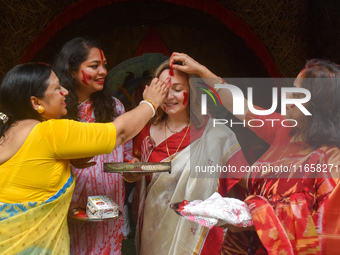 Hindu women apply ''sindhur,'' or vermillion powder, to a foreigner's face after worshipping the idol of the Hindu goddess Durga on the last...